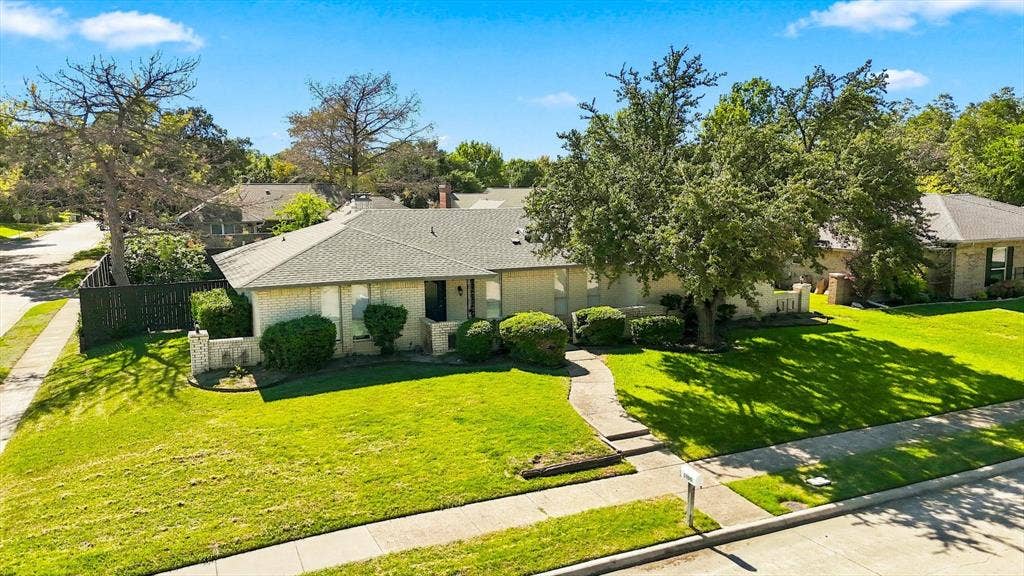 1900 Ports O Call Drive, Plano, TX 75075 Single-story residence featuring a light-toned masonry exterior, a multi-gabled shingle roof, a concrete walkway, and an expansive lawn with mature trees
