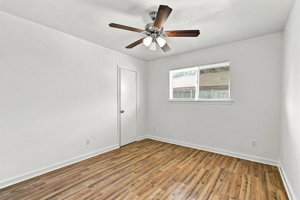 1900 Ports O Call Drive, Plano, TX 75075 Interior room featuring wood-finish flooring, a multi-blade ceiling fan with integrated lighting, and a single-panel interior door