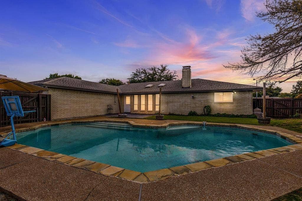 1900 Ports O Call Drive, Plano, TX 75075 Exterior featuring a brick facade, chimney, in-ground swimming pool with stone coping, and fenced perimeter