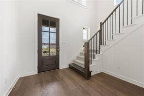 15638 Kestrel Mews, Frisco, TX 75035 Entryway featuring dark-toned wood-finish flooring, a multi-pane glass-panel front door, and a staircase with stained wood newel posts and dark metal balusters