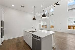 15638 Kestrel Mews, Frisco, TX 75035 Kitchen featuring an island with a stone countertop, an undermount stainless steel sink, built-in stainless steel appliances, wood-finish flooring, and pendant lighting