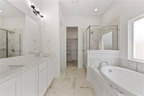 15638 Kestrel Mews, Frisco, TX 75035 Bathroom featuring a dual-sink vanity with white cabinetry, quartz-style countertops, an enclosed glass-paneled shower, and a soaking tub
