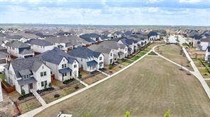 15638 Kestrel Mews, Frisco, TX 75035 Aerial perspective of a residential development featuring single-family dwellings with multi-pitch roofs, masonry exteriors, concrete walkways, and an expansive common green space