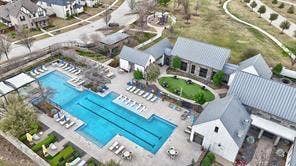 15638 Kestrel Mews, Frisco, TX 75035 Aerial perspective of a multi-structure facility featuring a lap pool, stone-finish buildings with standing seam metal roofing, and a manicured central lawn