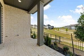 15638 Kestrel Mews, Frisco, TX 75035 Covered patio featuring stone tile flooring, brick exterior walls, and a metal railing