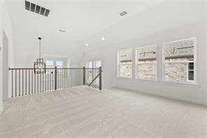 15638 Kestrel Mews, Frisco, TX 75035 Open-concept space featuring vaulted ceilings, neutral wall-to-wall carpeting, metal spindle railing, and a geometric pendant light fixture