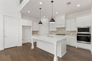 15638 Kestrel Mews, Frisco, TX 75035 Kitchen featuring white shaker-style cabinetry, center island with stone-finish countertop, dual stainless steel wall ovens, recessed lighting, and wood-finish flooring