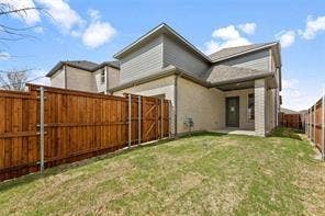 15638 Kestrel Mews, Frisco, TX 75035 Rear exterior featuring light-toned brick masonry, wood-finish horizontal siding, a covered patio, and a fully enclosed wood privacy fence