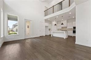 15638 Kestrel Mews, Frisco, TX 75035 Vaulted ceilings, wood-finish flooring, island kitchen with pendant lighting, and a second-story mezzanine railing