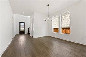 15638 Kestrel Mews, Frisco, TX 75035 Open-concept room featuring wide-plank wood-finish flooring, dual windows with stone veneer accents, and a tiered multi-light chandelier