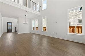 15638 Kestrel Mews, Frisco, TX 75035 Double-height living area featuring wood-finish flooring, a metal balcony railing, large picture windows, and a multi-light pendant fixture