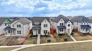 15638 Kestrel Mews, Frisco, TX 75035 Residential streetscape featuring multi-story dwellings with stone and brick exteriors, pitched roofs, covered front porches, and concrete walkways