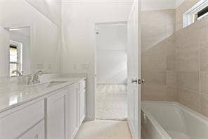 15638 Kestrel Mews, Frisco, TX 75035 Bathroom featuring white cabinetry, quartz vanity countertop, integrated sink, chrome dual-handle faucet, and tile-surround bathtub