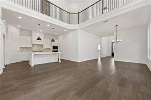 15638 Kestrel Mews, Frisco, TX 75035 Open-concept floor plan featuring wood-finish flooring, two-story ceiling, mezzanine balcony with metal railing, and kitchen with central island and recessed lighting