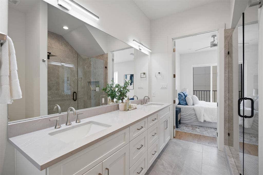 Double vanity featuring white cabinetry, quartz countertops, undermount sinks, and a full-width mirror