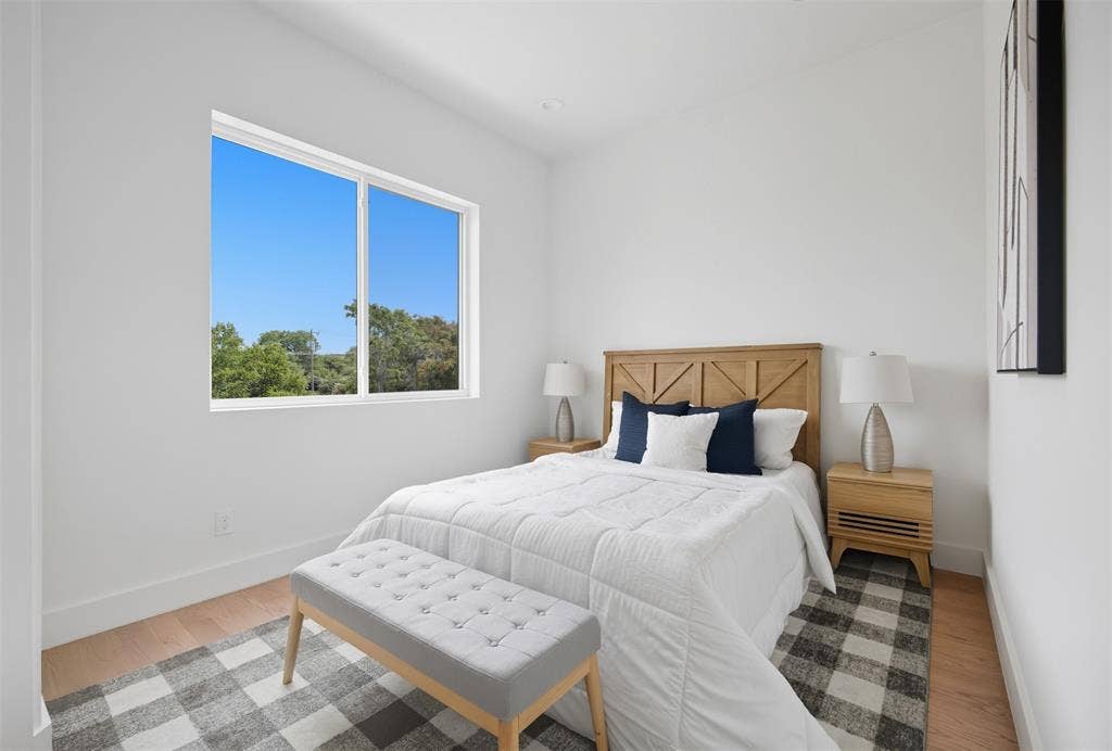 Neutral interior featuring wood-finish flooring, a large sliding window, and crisp white wall paint