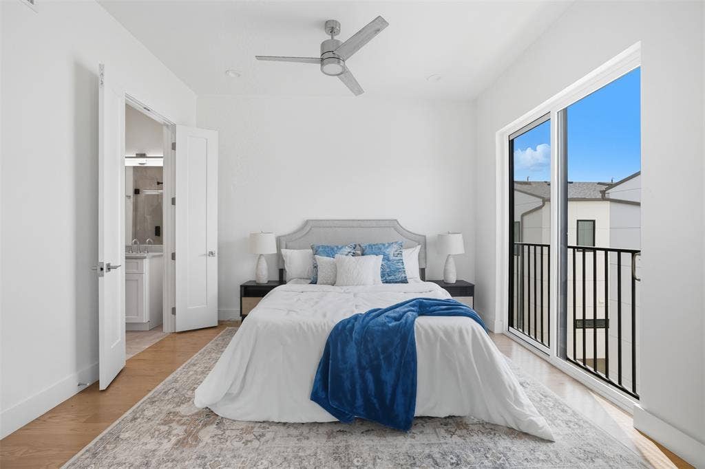 Sliding glass doors featuring a black metal railing, wood-finish flooring, brushed nickel ceiling fan, and solid-core interior doors