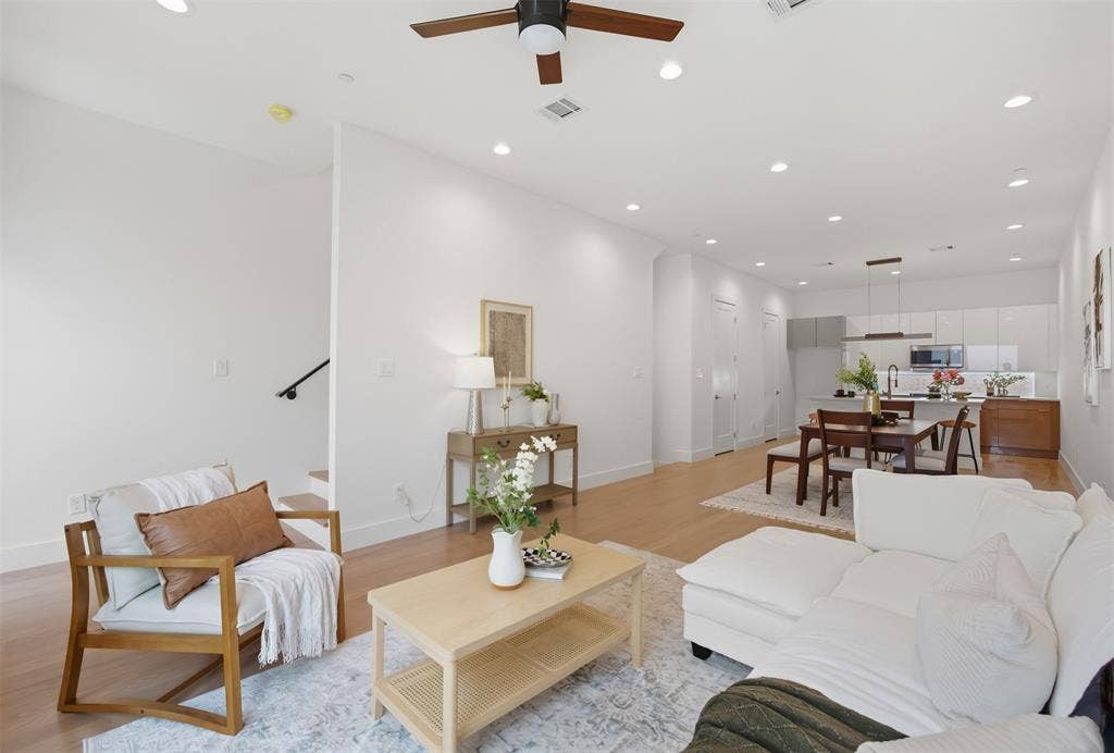 Open-concept interior featuring wood-finish flooring, recessed lighting, and a modern kitchen with high-gloss cabinetry and a central island