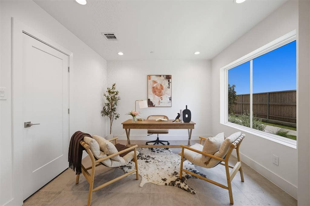 Neutral-toned tile flooring, recessed ceiling lighting, and a large horizontal window with exterior privacy fencing