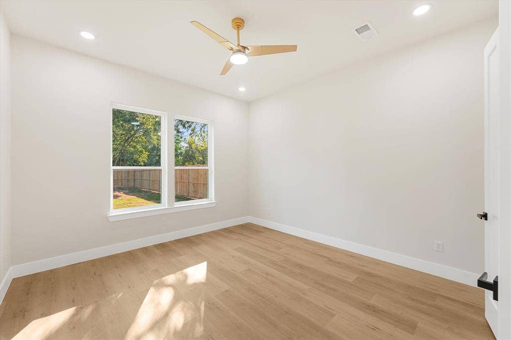 Room featuring wood-finish flooring, recessed lighting, a modern ceiling fan with integrated light, and dual pane windows