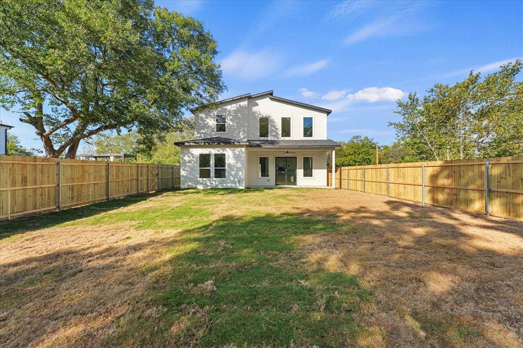 Two-story exterior with light-colored siding, covered rear patio, and wood privacy fencing enclosing the backyard