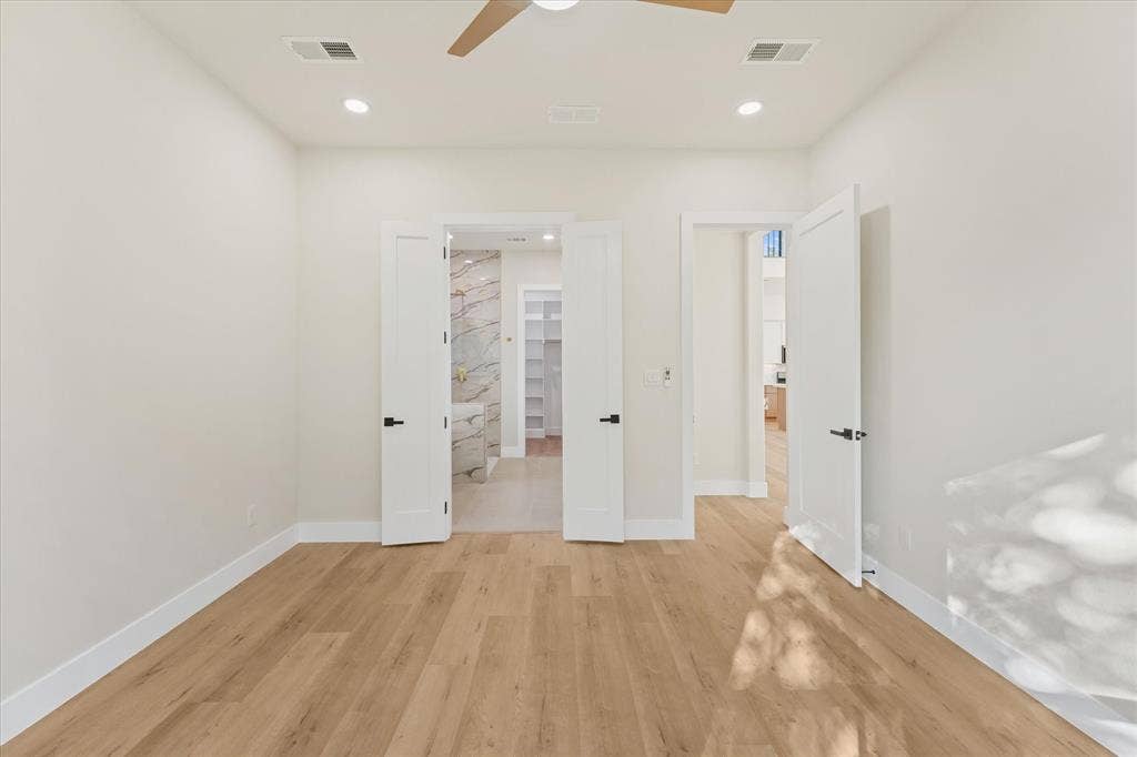 Room featuring wood-finish flooring, recessed lighting, a ceiling fan, and double interior doors with matte black hardware
