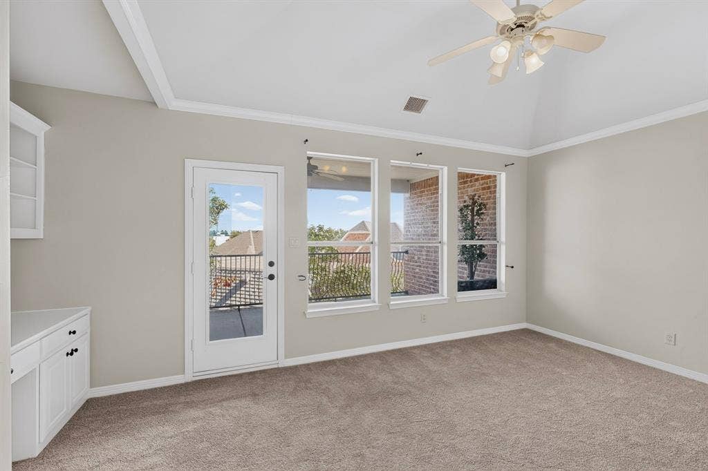 18359 Frankford Lakes Circle, Dallas, TX 75252 Vaulted ceiling with integrated ceiling fan, built-in cabinetry, carpeted flooring, and glass-paneled door with access to a railed balcony