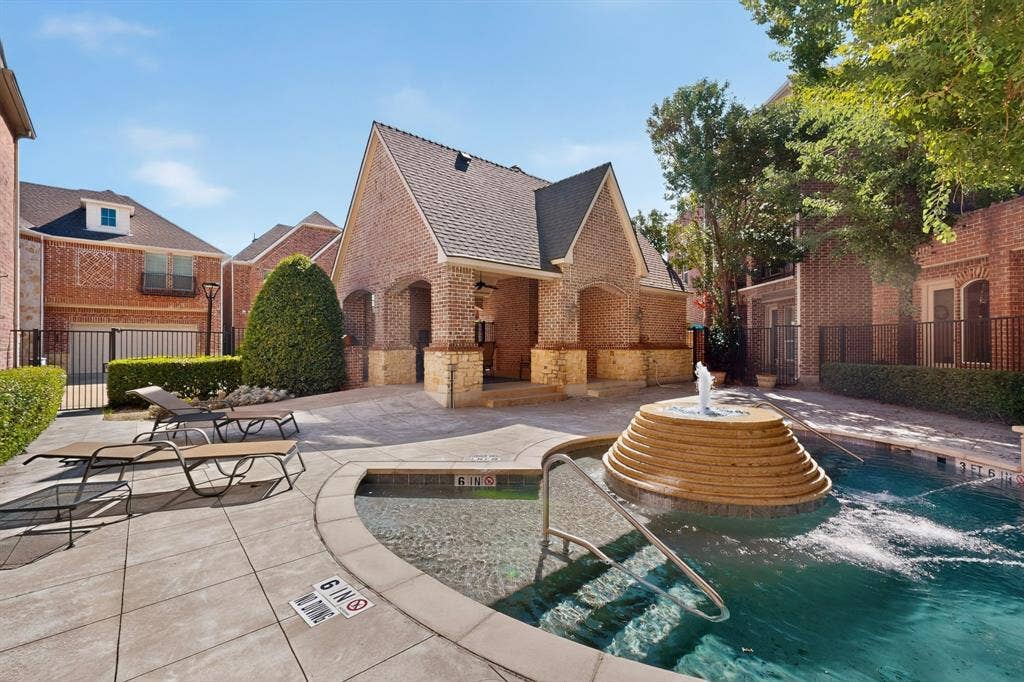 18359 Frankford Lakes Circle, Dallas, TX 75252 Community swimming pool featuring a stepped stone fountain, paved deck, and a brick-constructed pavilion with stone accents