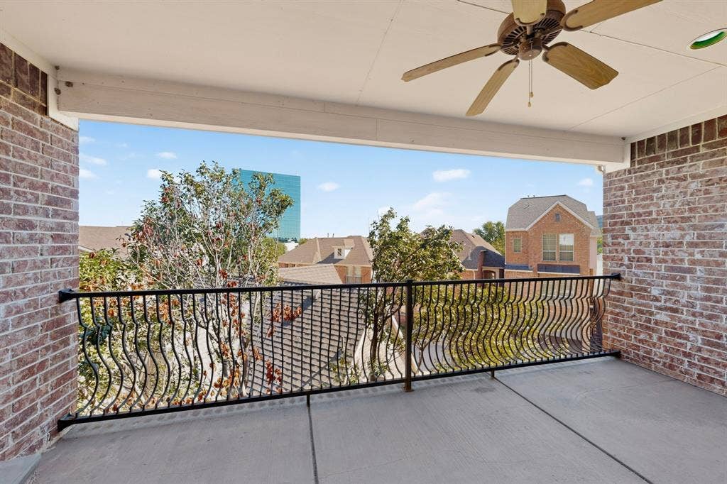 18359 Frankford Lakes Circle, Dallas, TX 75252 Covered balcony featuring brick masonry walls, wrought iron railing, and a ceiling-mounted fan