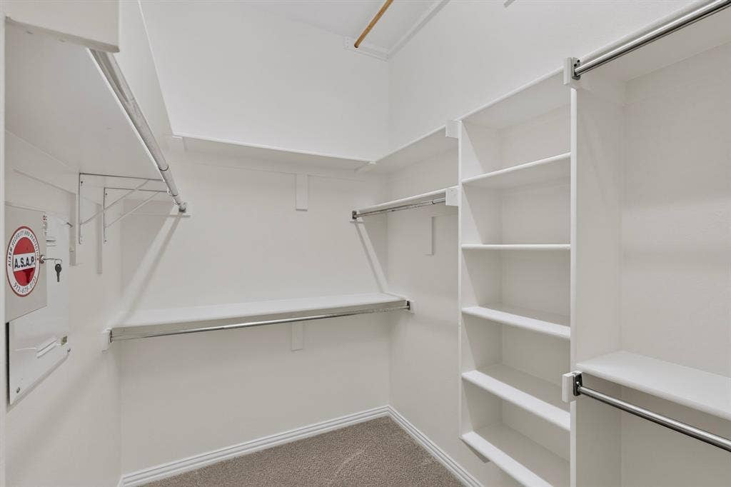 18359 Frankford Lakes Circle, Dallas, TX 75252 Walk-in closet featuring custom white built-in shelving, multiple tiered hanging rods, and neutral carpeting