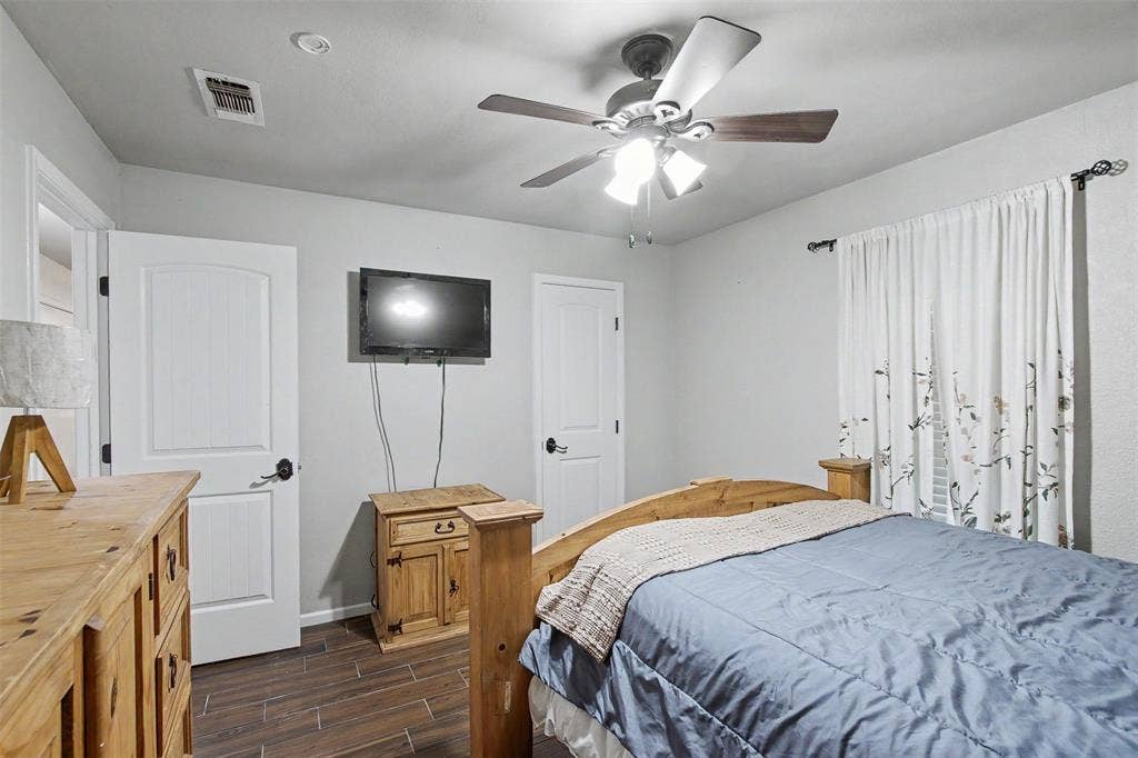 Room featuring wood-finish tile flooring, ceiling fan with integrated lighting, and two-panel interior doors with matte black hardware