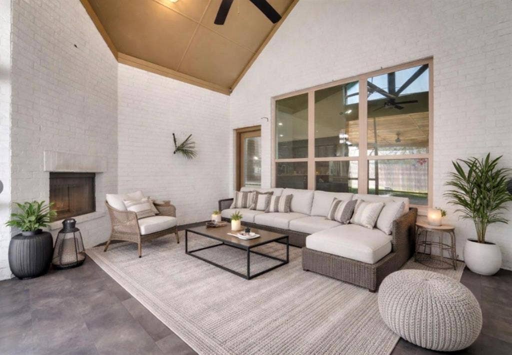 102 Champion Drive, Wylie, TX 75098 Covered patio featuring white brick walls, vaulted ceiling, large multi-pane windows, and a built-in fireplace
