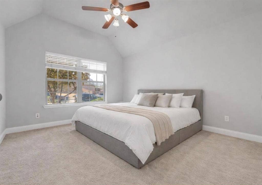 102 Champion Drive, Wylie, TX 75098 Vaulted ceiling with a centrally mounted ceiling fan, neutral wall tones, carpeted flooring, and a large multi-pane window