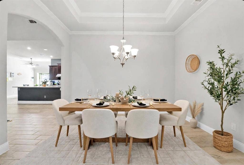 102 Champion Drive, Wylie, TX 75098 Dining area featuring a tray ceiling, arched entryway, and multi-arm chandelier