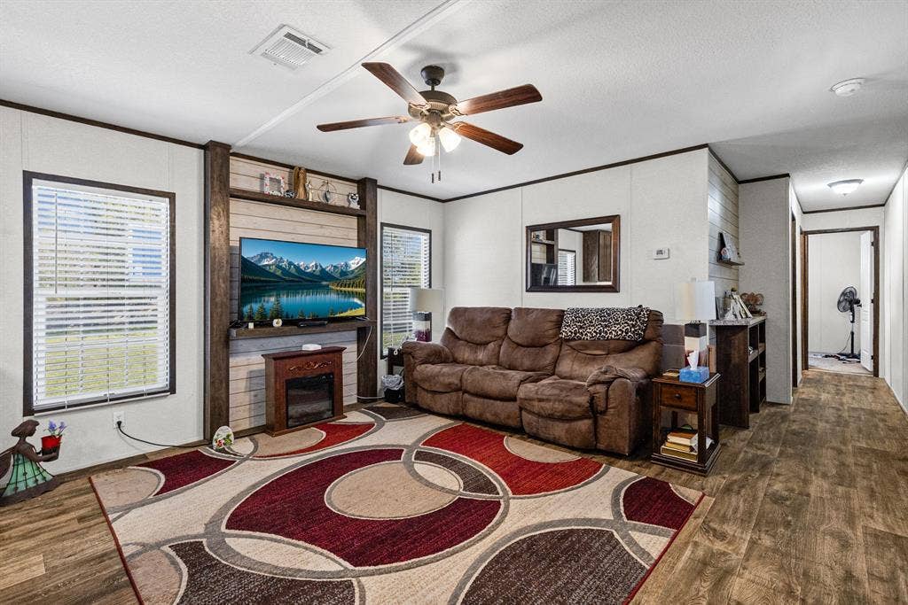 Living area featuring wood-finish flooring, a ceiling fan with integrated lighting, and a custom built-in media center with horizontal wood-plank detailing
