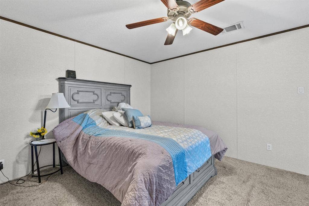 Neutral-toned wall panels featuring crown molding and a central ceiling fan with multi-blade finish and integrated light fixture