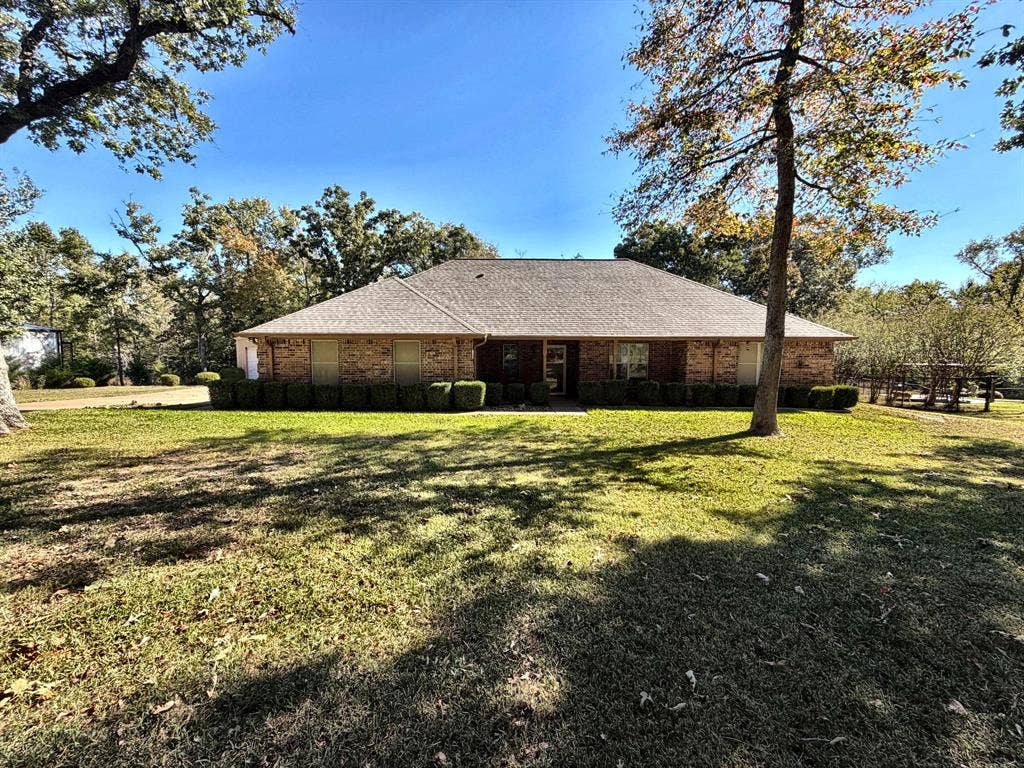9031 Mallard Way, Larue, TX 75770 Single-story brick exterior featuring a hip roof, large front yard, and mature canopy trees