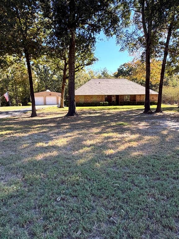 9031 Mallard Way, Larue, TX 75770 Brick exterior residence featuring a hip roof, multi-car detached garage, and mature trees situated on a spacious lot