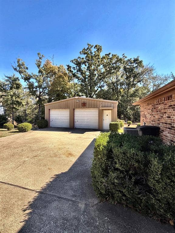 9031 Mallard Way, Larue, TX 75770 Detached two-car garage featuring metal siding, dual roll-up doors, a side-entry door, and an expansive concrete driveway