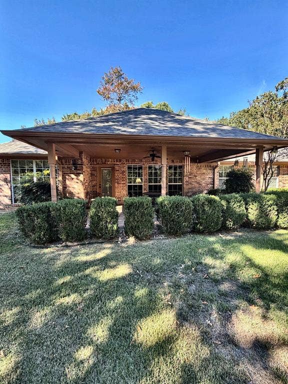 9031 Mallard Way, Larue, TX 75770 Brick exterior featuring a covered patio, hipped roofline, and mature landscaping
