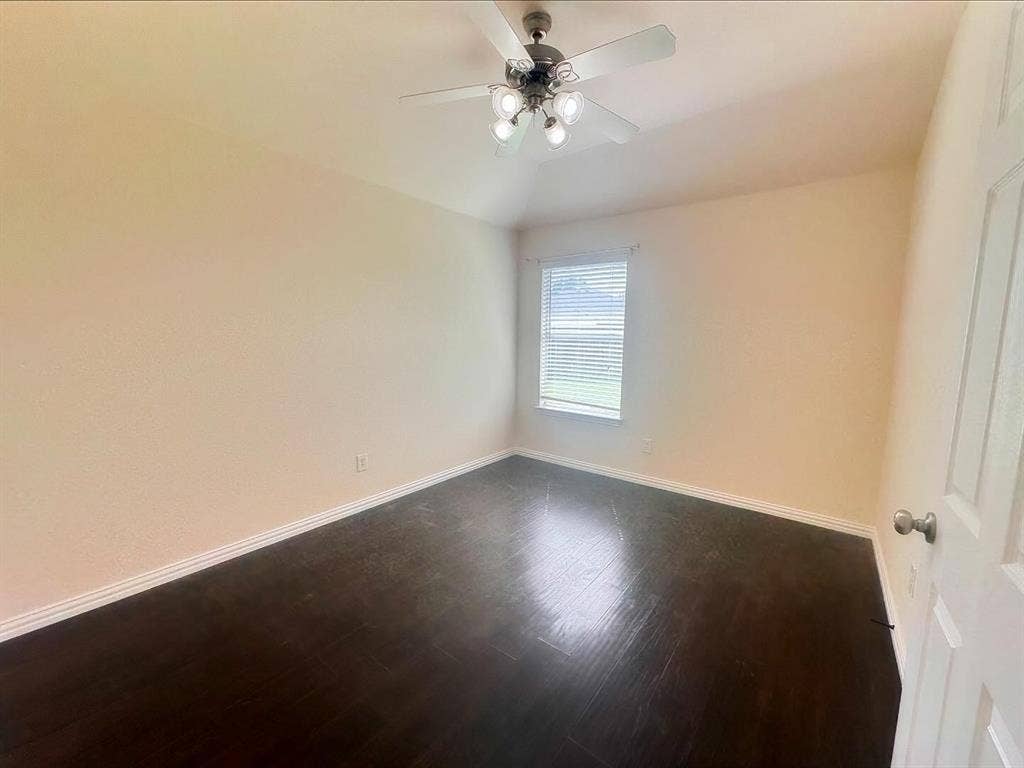 Spare room with vaulted ceiling, ceiling fan, and dark hardwood / wood-style floors