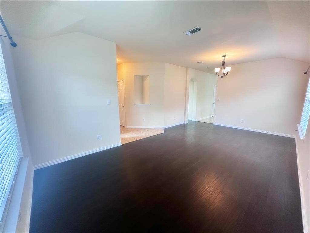 Spare room with lofted ceiling, a chandelier, hardwood / wood-style floors, and plenty of natural light
