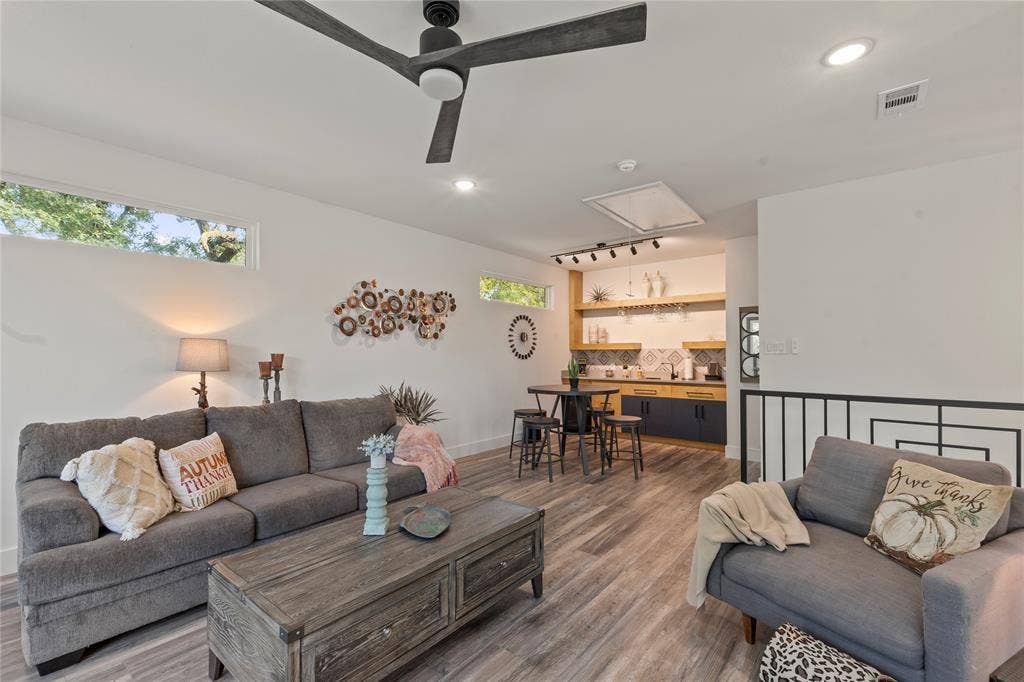 6113 Ottawa Trail, Mabank, TX 75156 Wood-finish flooring, matte black three-blade ceiling fan, transom windows, built-in wet bar with natural wood shelving, and patterned tile backsplash