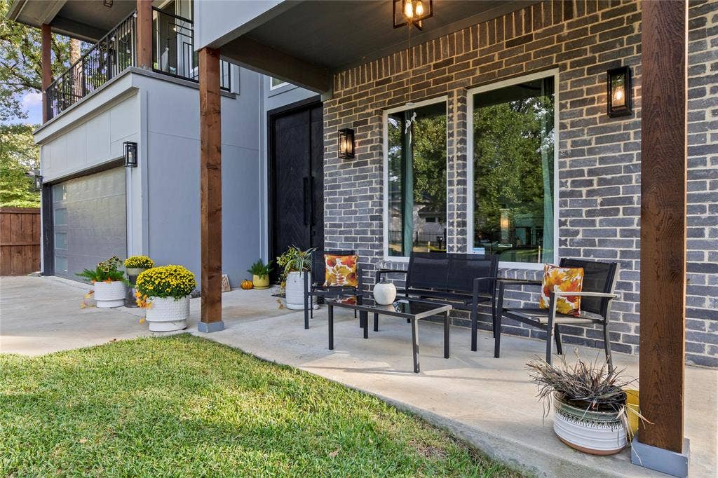 6113 Ottawa Trail, Mabank, TX 75156 Covered patio featuring a grey brick facade, exposed wood-finish posts, double front doors, large windows, and wall-mounted exterior lighting