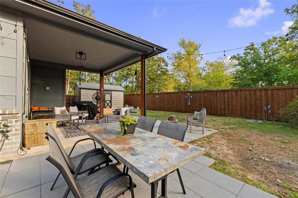 6113 Ottawa Trail, Mabank, TX 75156 Covered rear patio with large-format concrete pavers, wood-slat privacy fencing, and exterior string lighting