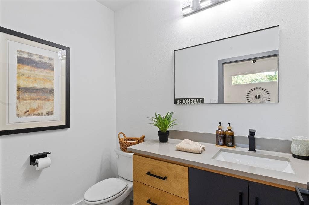 6113 Ottawa Trail, Mabank, TX 75156 Vanity featuring dual-tone cabinetry, stone-composite countertop with integrated sink, matte black faucet, and rectangular wall-mounted mirror