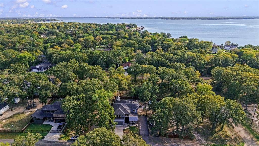 6113 Ottawa Trail, Mabank, TX 75156 Aerial perspective featuring a multi-story residence with a pitched roof, concrete driveway, and established canopy of mature trees