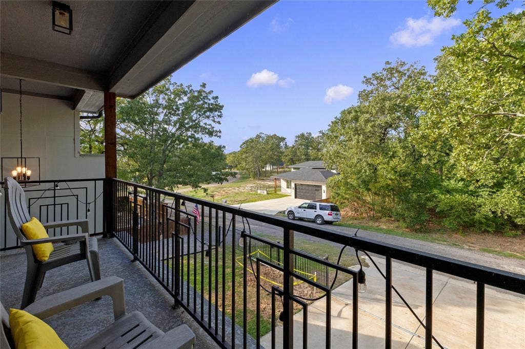 6113 Ottawa Trail, Mabank, TX 75156 Covered balcony featuring concrete flooring, black metal railing, and an attached overhead pendant light fixture
