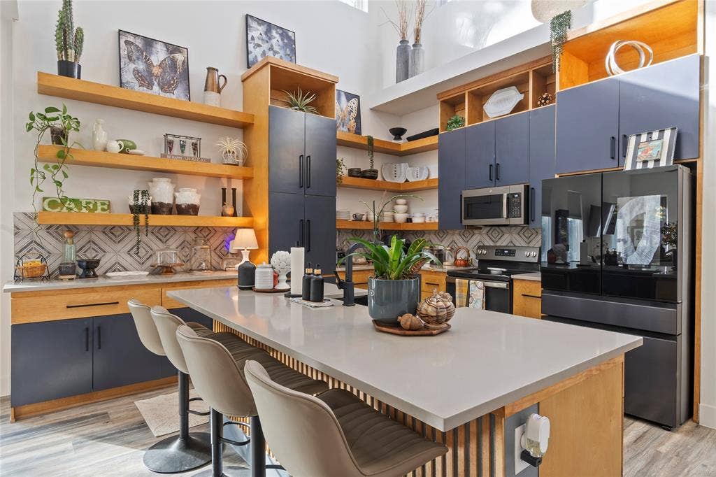 6113 Ottawa Trail, Mabank, TX 75156 Kitchen featuring dual-toned flat-panel cabinetry, open wood shelving, a quartz-topped island with vertical slat detailing, and a geometric patterned tile backsplash