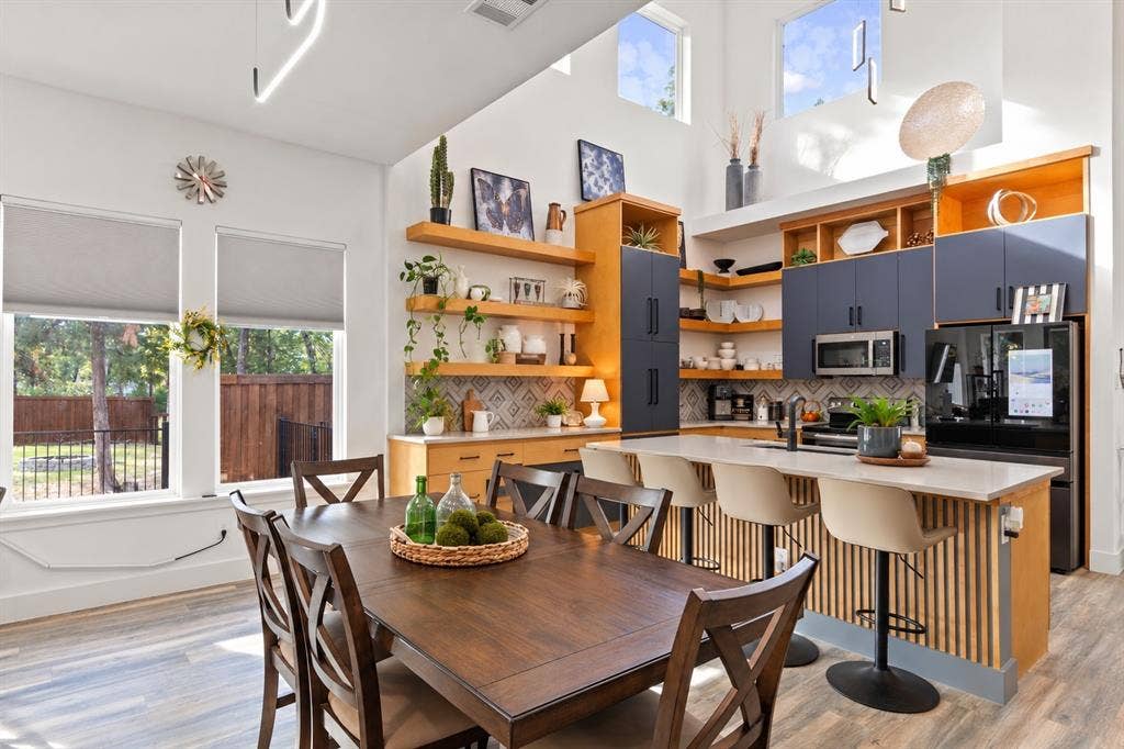 6113 Ottawa Trail, Mabank, TX 75156 High-ceiling kitchen featuring a dual-toned cabinetry finish, wood-finish flooring, floating wood shelving, a central island with a slatted wood base, and geometric tile backsplash
